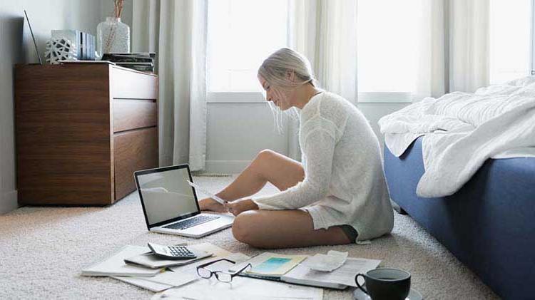 Woman searches through paperwork and on her laptop for a new apartment.