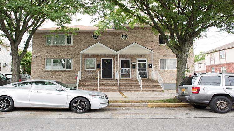 Brick condo building with vehicles parked in front.